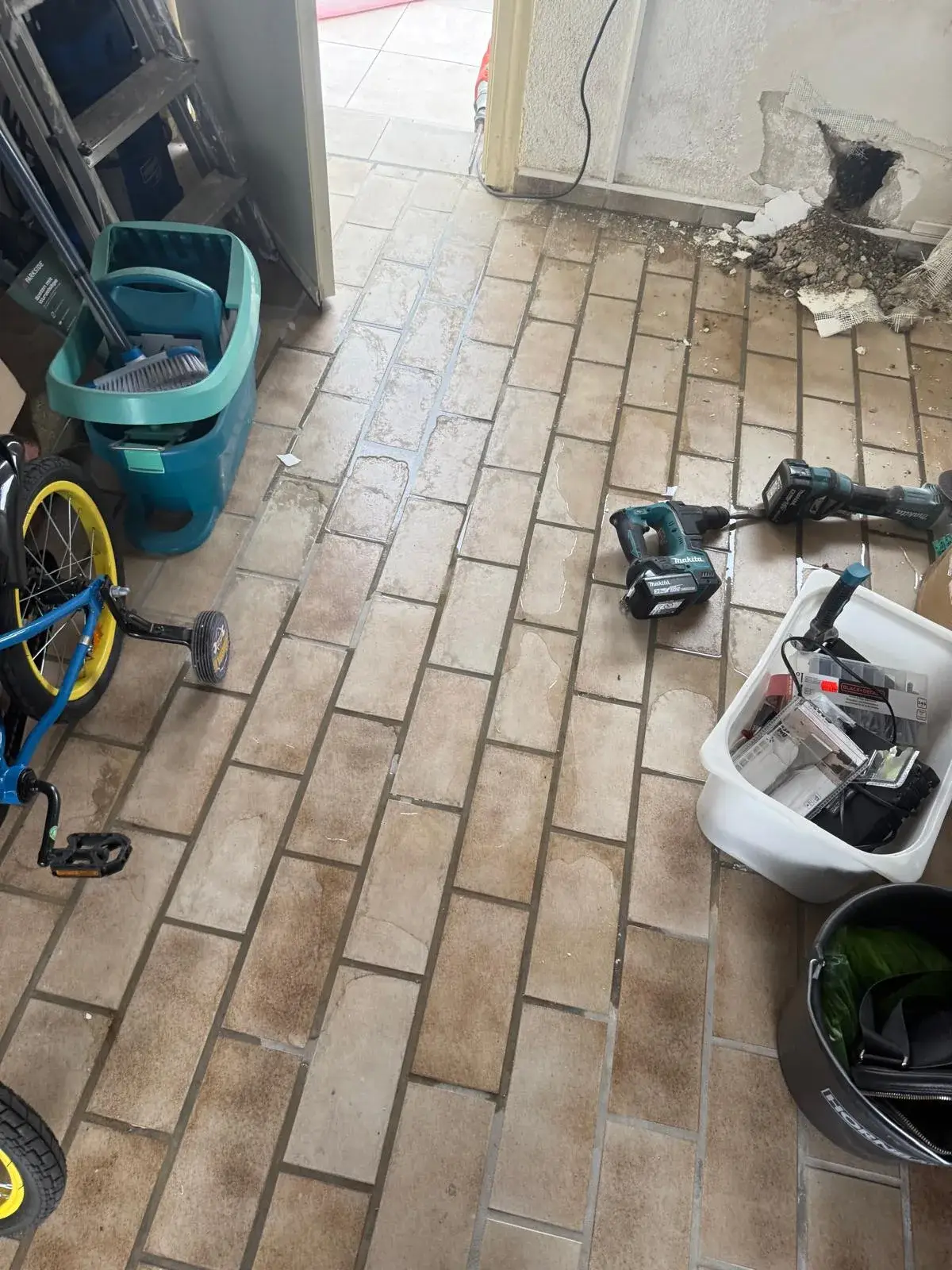 Feuchtigkeitsschaden im Wohnbereich mit geöffneter Wand und Wasser auf dem Fliesenboden